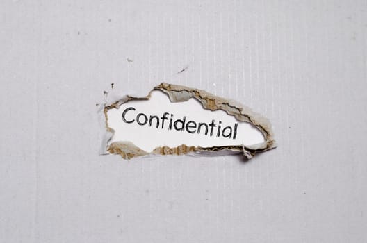 The word confidential appearing behind torn paper.