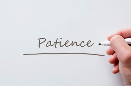 Human hand writing patience on whiteboard