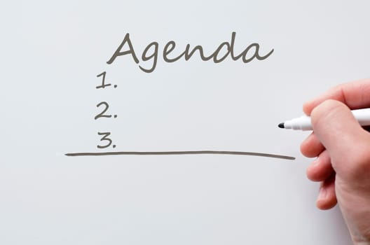 Human hand writing agenda on whiteboard