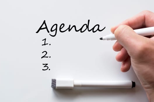 Human hand writing agenda on whiteboard