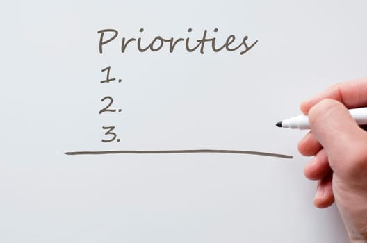 Human hand writing priorities on whiteboard