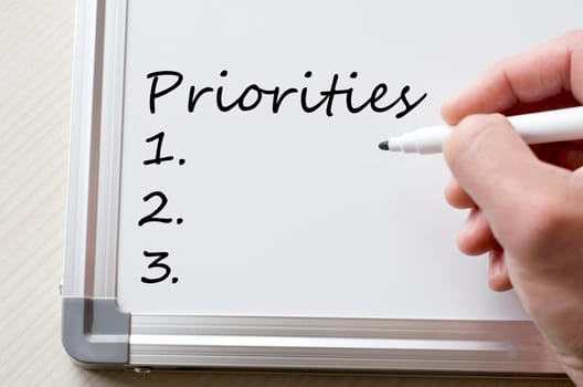 Human hand writing priorities on whiteboard