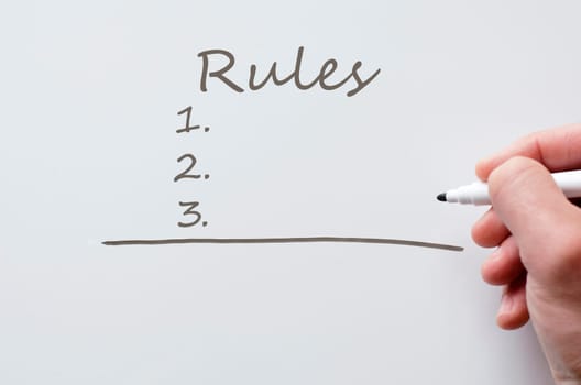 Human hand writing rules on whiteboard