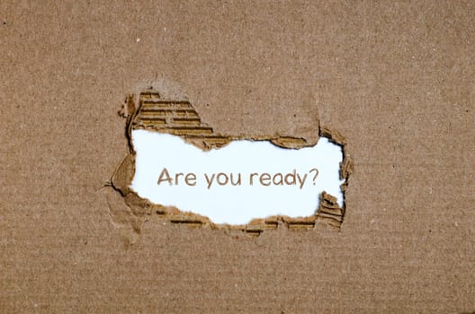 The word are you ready appearing behind torn paper.