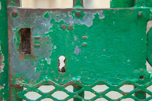 A green rusty lock on an iron door