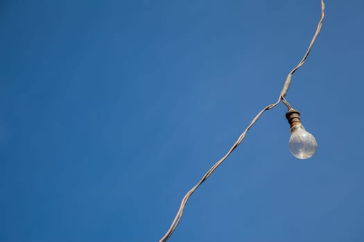 A dusty lamp attached to his wire over a blue sky