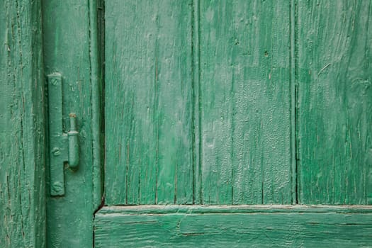 Recently painted green wood door and window panels with hinge