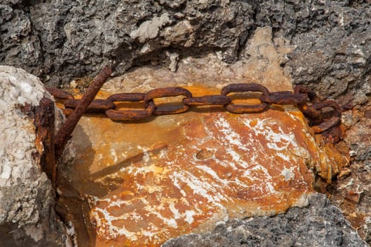 Chain ruined by time and rust on a beach
