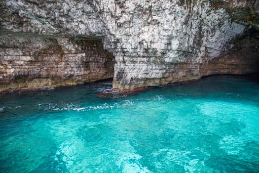 Caves in a multi coloured rocks over a lightblue water in mediterranean sea