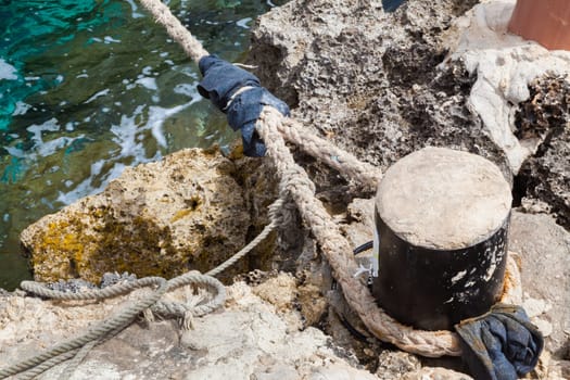 Weathered boat rope hanged to a stone