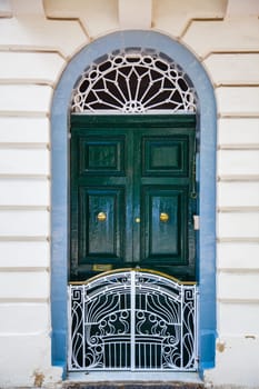 A geen wood door with white small fence and blue frame
