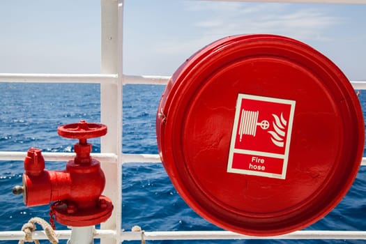 Red fire extinguisher with pipe connector on a boat