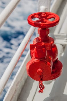 Red fire extinguisher with pipe connector on a boat