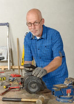 a man with antique car generator in his workshop