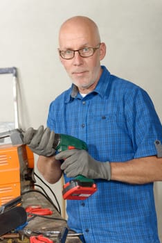 a mature man with a drill in his workshop