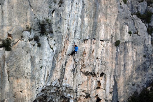 Young Man Climbing a Cliff of Mountain