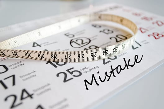 Mistake text concept over tape measure and calendar background..
