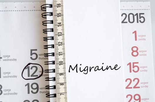 Migraine text concept over tape measure and calendar background..