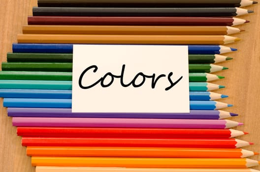 Colors text concept and colored pencil on wooden background
