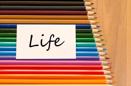 Life text concept and colored pencil on wooden background