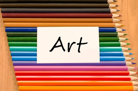 Art text concept and colored pencil on wooden background