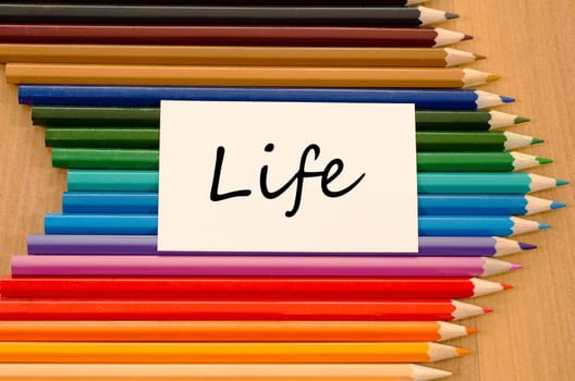 Life text concept and colored pencil on wooden background