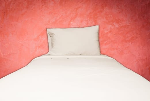 Close up white bedding sheets and pillow on red wall background