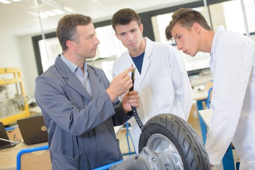 Teacher showing students the adapter for inflating tyre