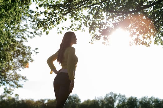 blonde girl with a beautiful figure in shirt and jeans, standing at sunset on open silhouette, the silhouette picture