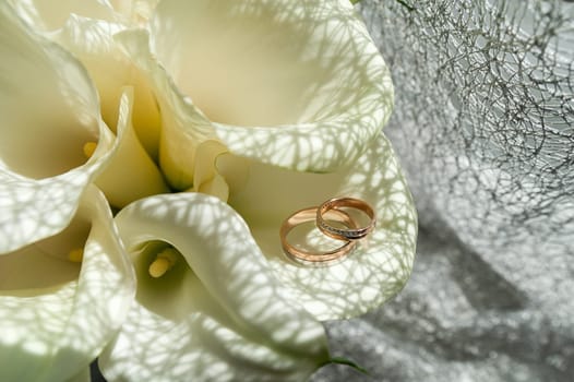 Wedding bouquet of white Calla Marsh Marsh, Bog Arum, Water-Arum, Araceae family. the light of the morning sun, the newlyweds rings