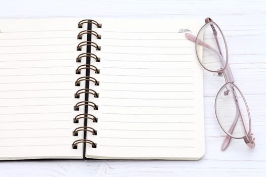 Ladies glasses and notebook on the white wooden table