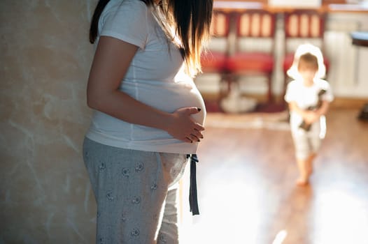 Pregnant woman standing on the background plays the eldest daughter. at home