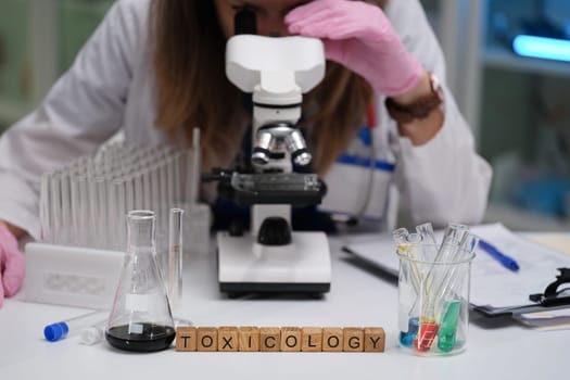 A dedicated scientist is meticulously examining various samples under a microscope in a specialized toxicology lab