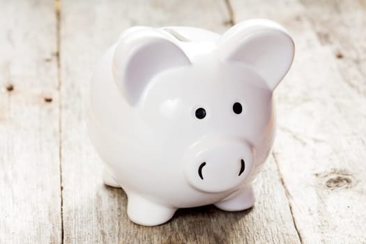 White piggy bank on the old wooden background