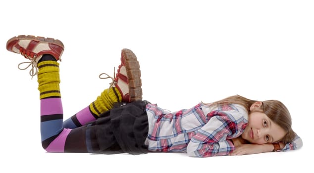 preteen girl in hipster style, lying on the floor, isolated on white background