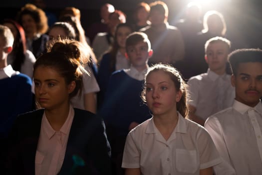 Crowd of teenage students in a lecture hall. They are looking towards the speaker, who can't be seen.
