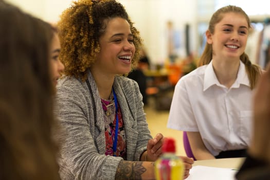Young female teacher having a laugh with her students during lesson.