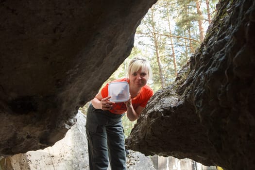 A female geocacher with a geocache container in a forest