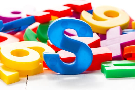 Blue letter S in a front of other colorful plastic letters.