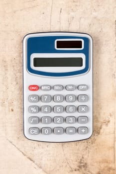 Electronic digital calculator on dirty canvas background