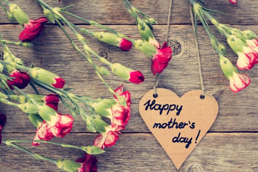 Heart shaped mothers day card with carnations on wood background