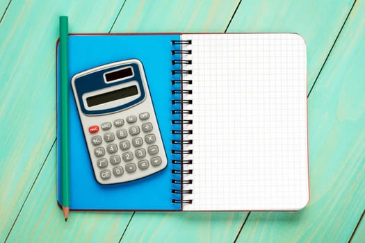 Electronic calculator and open notebook with squared sheet for copy-space