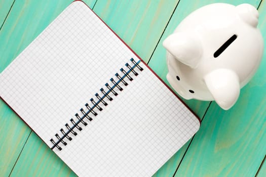 Piggy bank and open notebook, top view