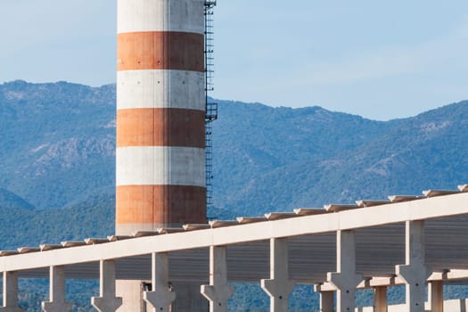 red and white chimney with industrial building