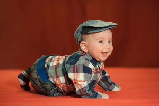Cute baby in a tweed flat cap with a red background, the child&#39 s emotions