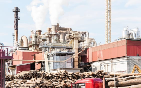 industrial plant of a furniture factory with smoking smokestacks,tubes,silos,crane ,truck and trunks.