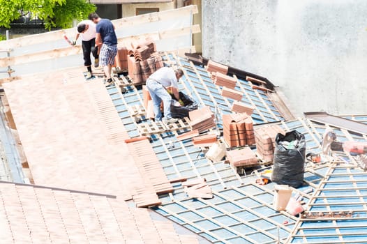 Udine , Italy - May 26 2016 : Construction site. Masons to work on the roof for laying tiles