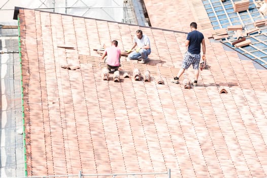 Udine , Italy - May 26 2016 : Construction site. Masons to work on the roof for laying tiles