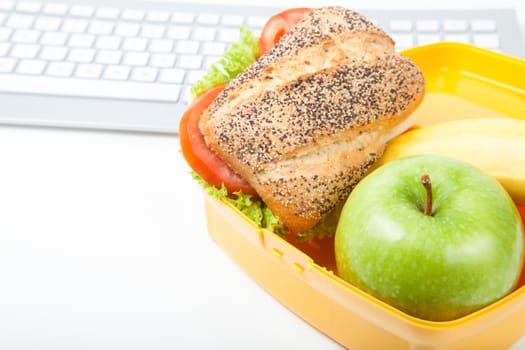 lunchbox with sandwich an apple and keyboard