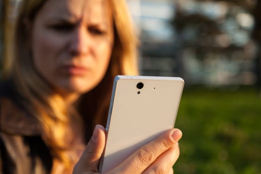 annoyd woman with smartphone in sunlight